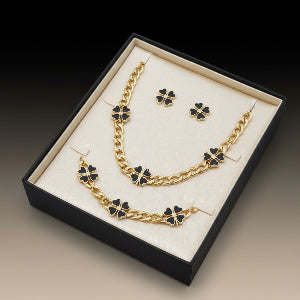 Gold necklace and earrings set in a black box on a red background